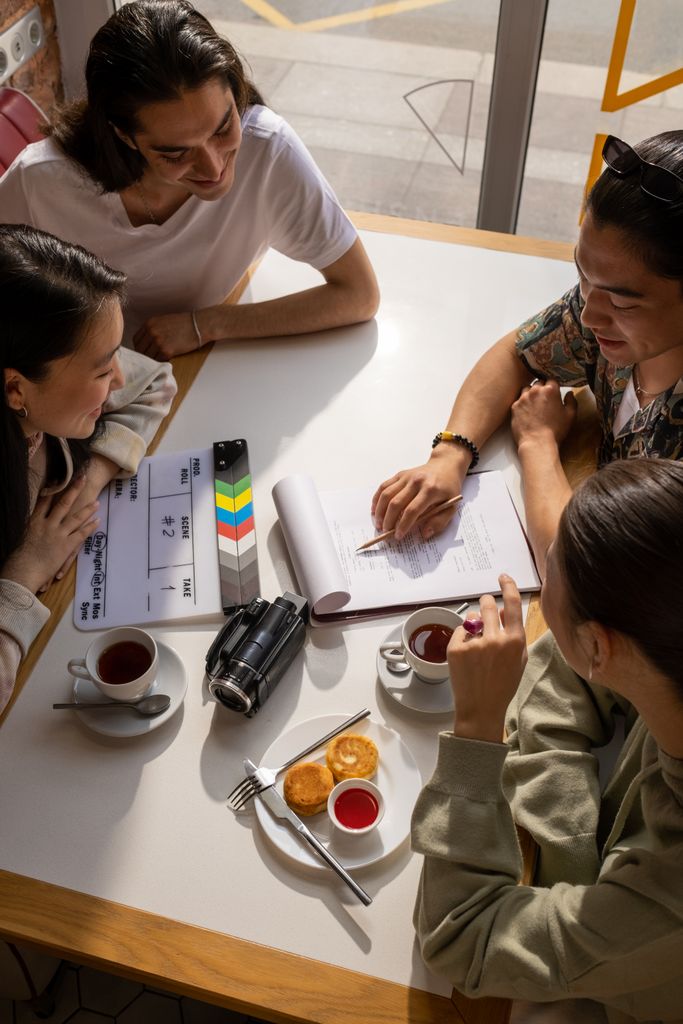 A group of adults discusses plans over tea and snacks in a cozy café setting.