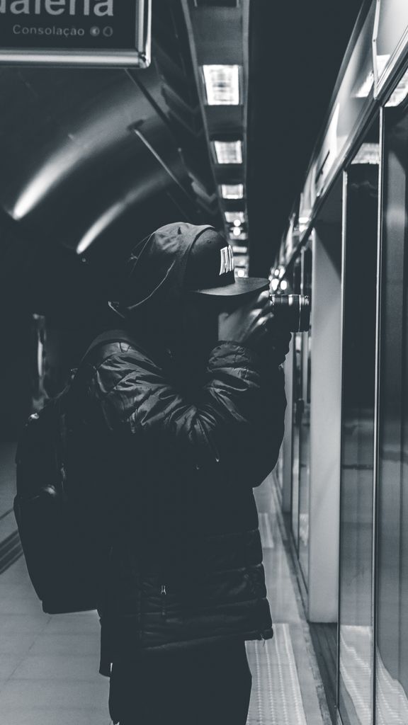 A man taking photos in an urban subway, captured in black and white.